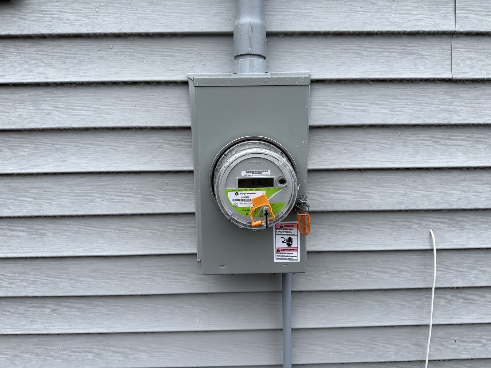 Canadian residential electrical kWh meter mounted on the side of a Maritime home representing the impact of NB Power rate increases on monthly household bills